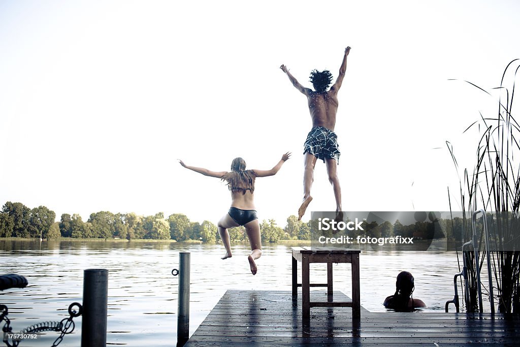 carefree día de verano: Adolescentes sumergiéndose en un lago - Foto de stock de Adolescencia libre de derechos