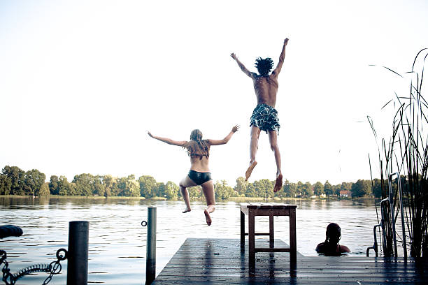 istock carefree summer day: teenagers jumping into a lake 175730752