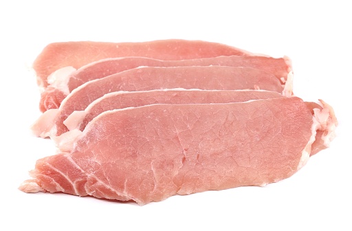 Uncooked thin pork loin steaks on white background.