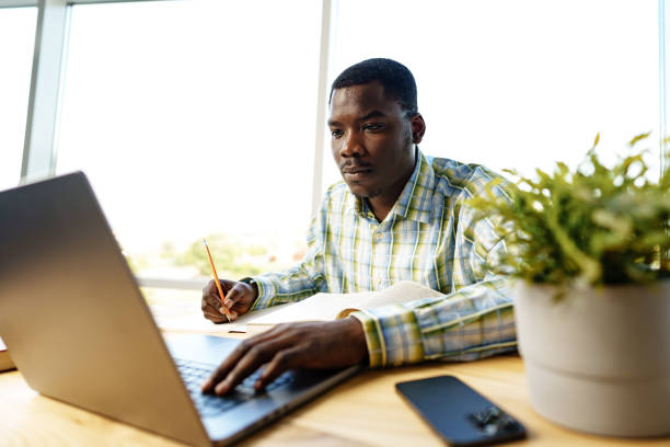 istock Serious concentrated african man studying or working with laptop indoors 1757327611