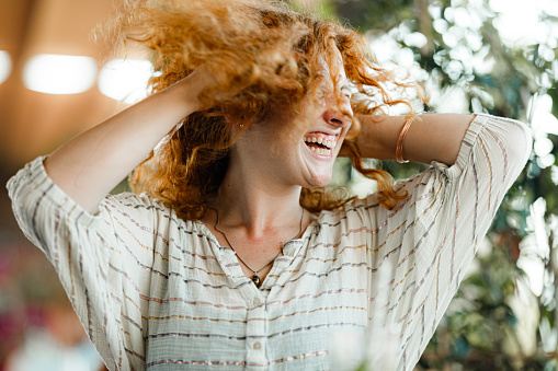 Young cheerful woman having fun while shaking her head with closed eyes.