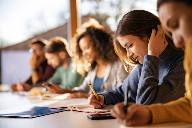 Estudante universitário sorridente escrevendo durante uma aula na universidade. - foto de acervo