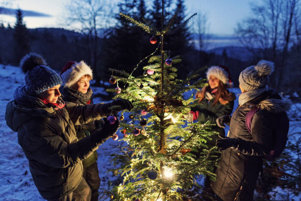 Teenagers decorating a Christmas tree in the forest
