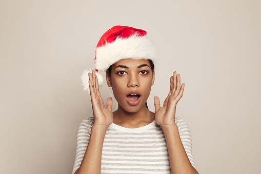 Young attractive surprised Christmas woman in red Santa hat, Xmas portrait