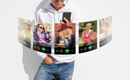 Concept of online dating. Man viewing girls profile photos in dating app on mobile phone.