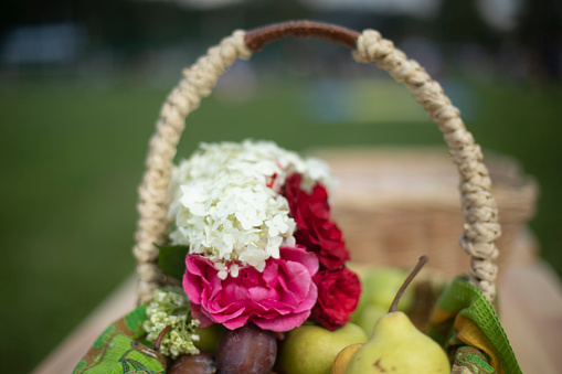 Basket with flowers. Flowers and fruits. Wicker basket. Flowers in garden.