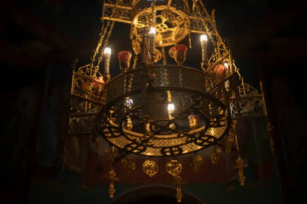 Photo of Chandelier in church. Golden chandelier in dark temple. Vintage interior.