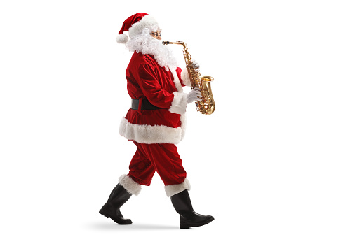 Full length profile shot of Santa claus walking and playing a sax isolated on white background