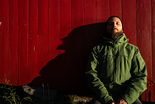 Bearded man portrait in winter Norwegian landscape. The men is wearing a warm jacket and a beanie