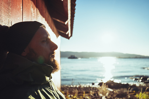 Bearded man portrait in winter Norwegian landscape. The men is wearing a warm jacket and a beanie