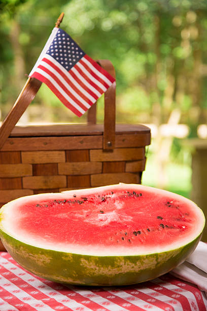 料理：スライスのスイカでピクニックテーブルを配しております。バスケットとアメリカの国旗。 - picnic watermelon tablecloth picnic table ストックフォトと画像
