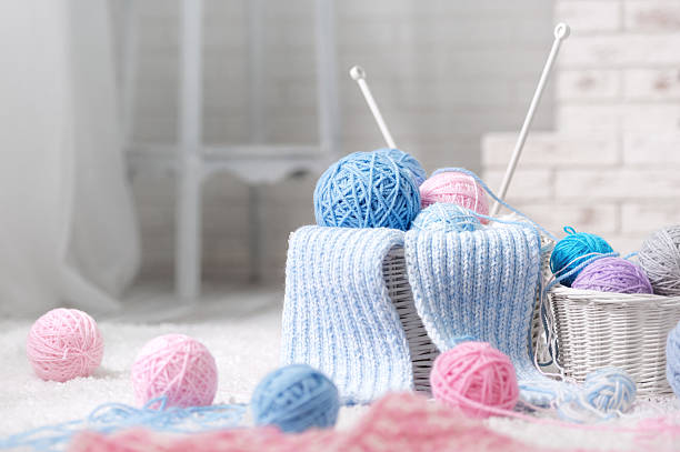 Wicker basket with a variety of balls of yarn on the carpet by the fireplace in the interior