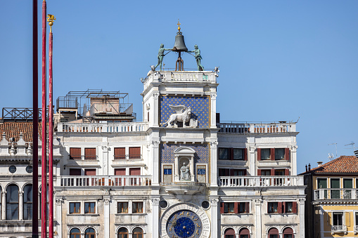 Venice, Italy - September 27, 2023: St Mark's Clock tower (Torre dellOrologio) on Piazza San Marco, Lion of Saint Mark relief on facade. Winged Lion of Venice is a symbol of the city.