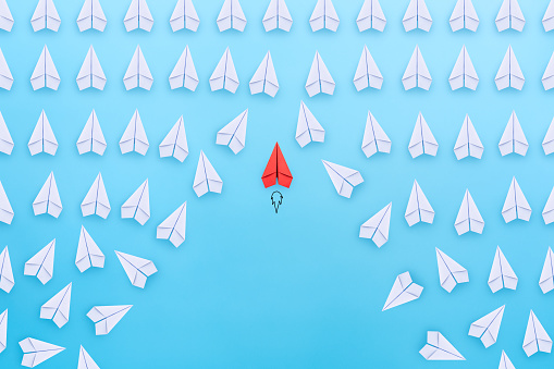 Business competition, successful businessman concept with Red paper plane flying overtake the other white paper planes on blue background.
