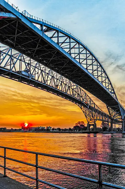 Bluewater Bridge spans the Saint Clair River from Port Huron Michigan USA to Sarnia Ontario Canada. The twin bridges are in silhouette against the rising sun.