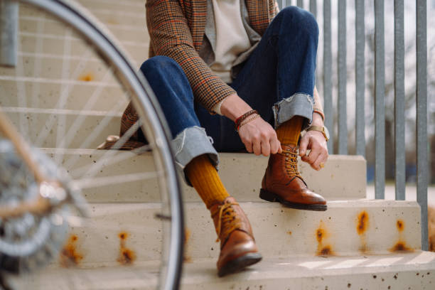 Businessman putting on elegant leather shoes. Preparing for bicycle ride.