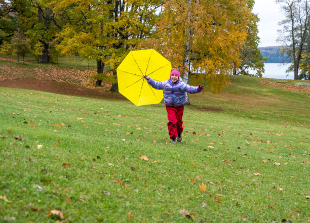 어린이, 백인 소녀, 8 세, 가을 산책. 밝은 노란색 우산을 쓴 아이가 기뻐하며 뛰어오르고 가을을 기뻐합니다. - female 8 9 years child excitement 뉴스 사진 이미지