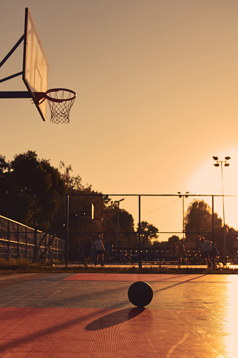 Basketball ball on a public playing court in golden hour time.