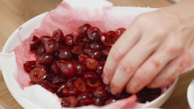Cherries, halved and pitted, in a white plate, a red-stained napkin.