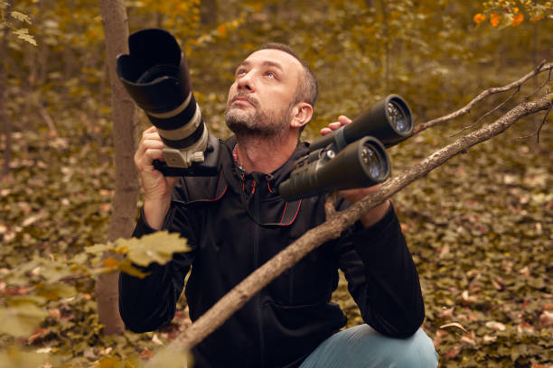 istock Man using binoculars and camera for birdwatching and other observing animals in nature. 1757463156