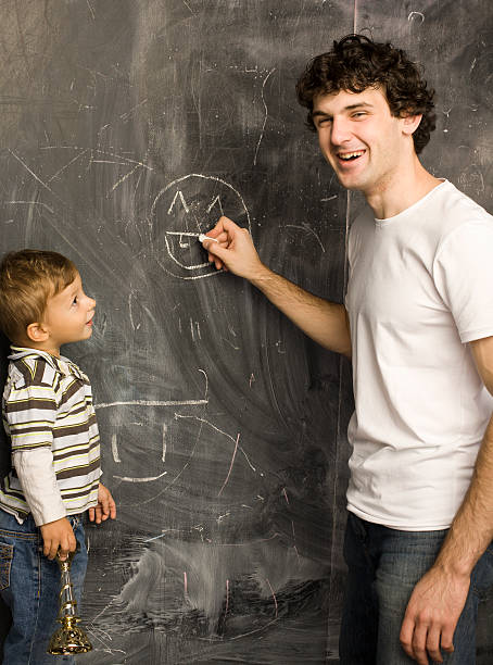 istock teacher and little student, father with son near blackboard 175746717