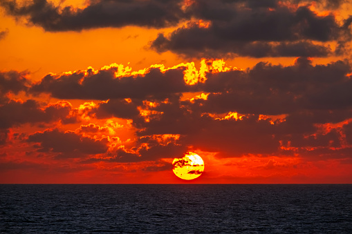 The sun setting over the horizon at sea.