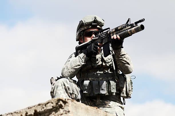 Keeping a watch-out Low angel view of a sniper crouched down on a roof of a building against a sky background guerrilla warfare photos stock pictures, royalty-free photos & images