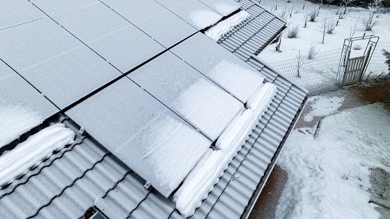 Closeup drone shot of snowy solar panels on a house roof