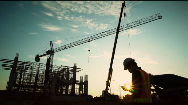 istock Silhouette of engineer using laptop to control work, crane, construction site 1757499601