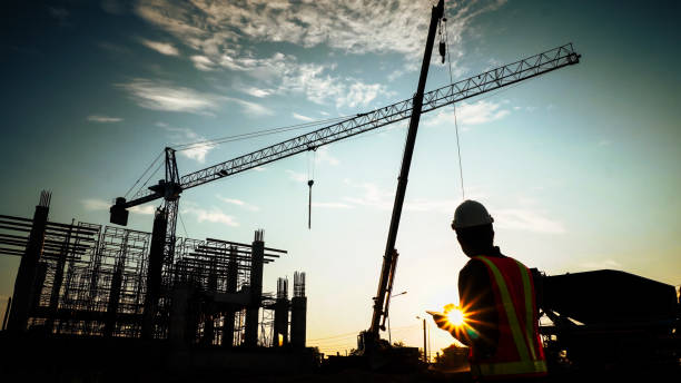 istock Silhouette of engineer using laptop to control work, crane, construction site 1757499627