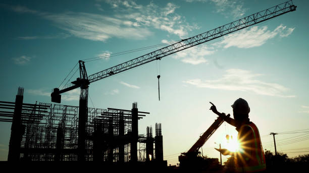 istock Silhouette of engineer using laptop to control work, crane, construction site 1757499631