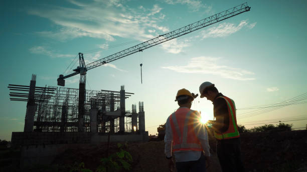 istock Silhouette of team engineer using laptop to control work, crane, construction site 1757499636