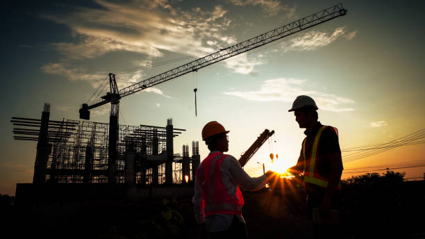 istock Silhouette of team engineer using laptop to control work, crane, construction site 1757499652