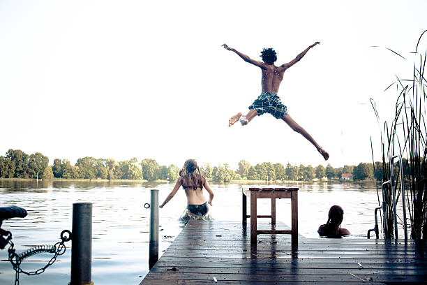 istock carefree summer day: teenagers jumping into a lake 175750796
