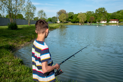 Young, red hair boy fishing in a lake