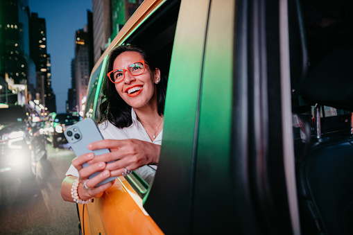 Hispanic adult woman riding a taxi in Manhattan looking out of the car window.