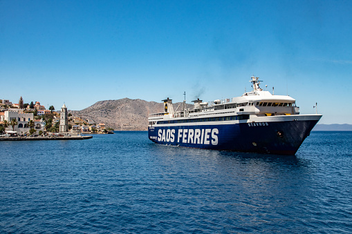 Symi, Greece - Jun 03, 2021.  A large ferry docking in the pictorial harbour on the Greek island of Symi island in Greece. Dodecanese.