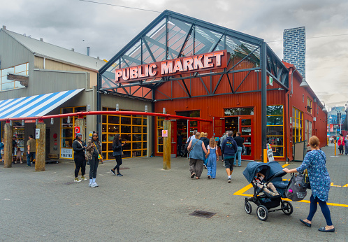 Pedestrians standing and walking outside Granville Island Public Market, Vancouver, Canada