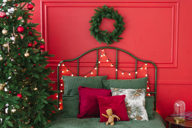 istock Bed with pillows and green linens near a Christmas tree with lights 1757534654