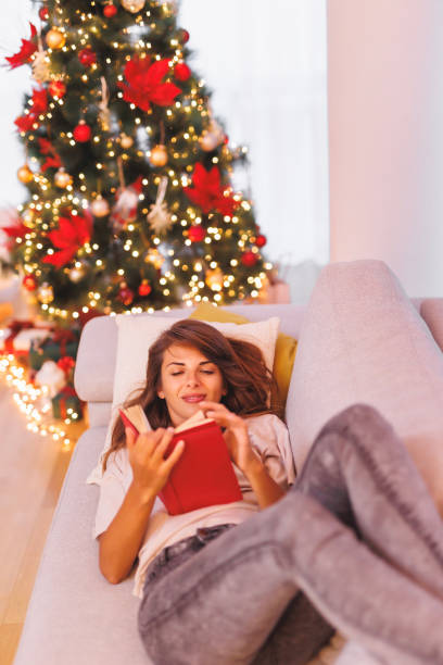 istock Woman reading a book by the Christmas tree 1757545760