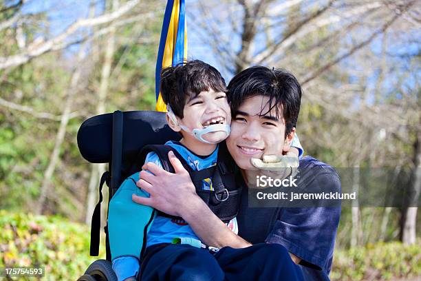 Poco Niño Para Personas Con Discapacidades En Silla De Ruedas Que Abrazan Más Brother Al Aire Libre Foto de stock y más banco de imágenes de Diversidad funcional