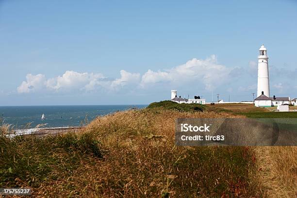 White Lighthouse Against Blue Sky And Sailing Boat On Sea Stock Photo - Download Image Now