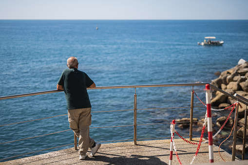 A man on the terrace admires the sea view - the observation deck is at a height - a romantic mood