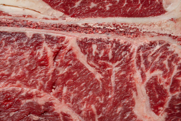 istock T-bone steak on a light wooden board, standing on a dark stone background, with salt and pepper mixed with peas scattered around. 1757557633