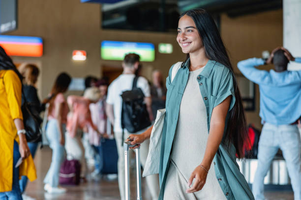 istock Beautiful Young Woman Pulling Her Gray Suitcase At The Airport 1757565342