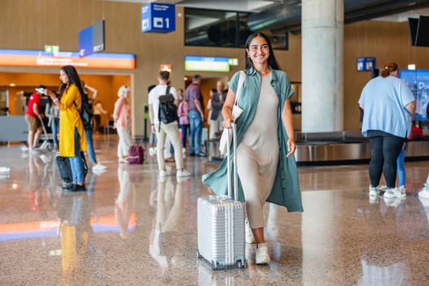 istock Smiley Young Woman Pulling Her Gray Suitcase At The Airport 1757565374