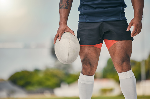 Rugby, man and ball, zoom on legs of strong, muscular male  ready for winning game on field. Fitness, sports and zoom on face of player at practice match, workout or competition on grass at stadium.