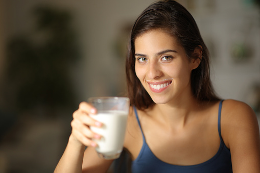 Happy woman posing holding milk glass in the night