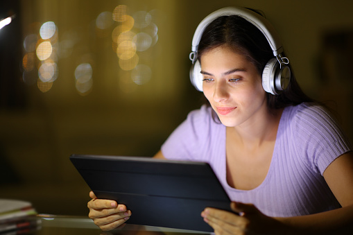 Woman in the night using headphone and tablet