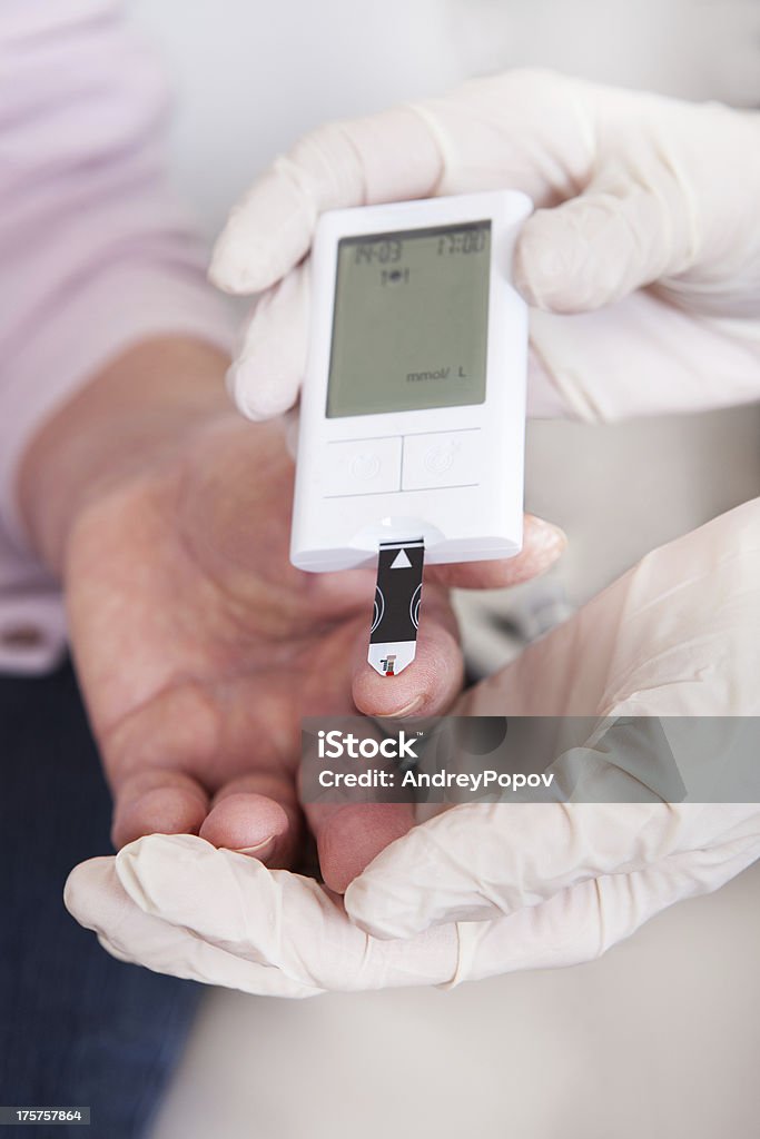 Medico controllando il livello di glucosio nel sangue - Foto stock royalty-free di Accudire
